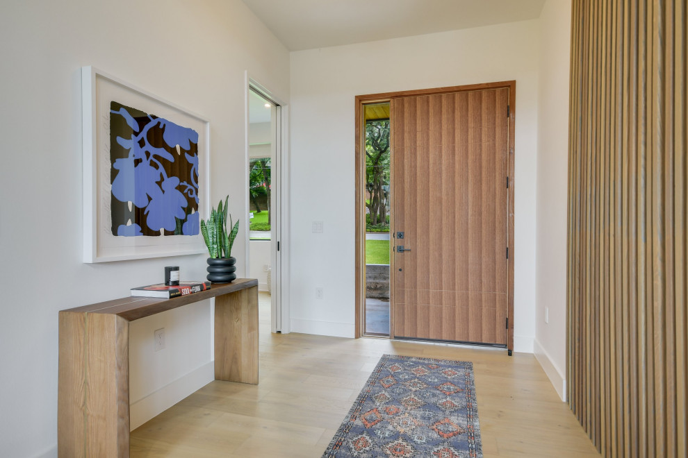 Photo of a mid-sized midcentury front door in Austin with white walls, light hardwood floors, a single front door and a medium wood front door.