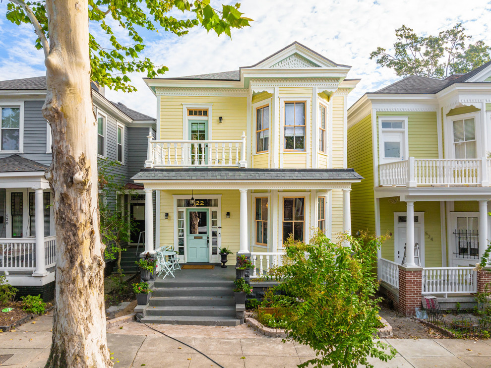 Large transitional yellow two-story wood and clapboard house exterior idea with a hip roof, a shingle roof and a gray roof