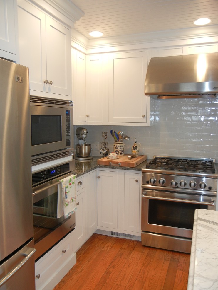 Example of a large transitional u-shaped medium tone wood floor, brown floor and shiplap ceiling open concept kitchen design with shaker cabinets, white cabinets, stainless steel appliances, an island, white backsplash, subway tile backsplash, a farmhouse sink and granite countertops