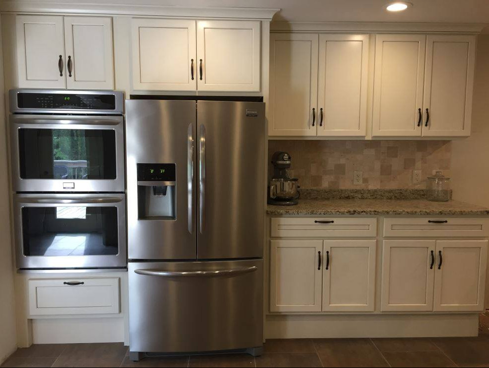 Example of a small transitional l-shaped medium tone wood floor and brown floor enclosed kitchen design with a double-bowl sink, shaker cabinets, white cabinets, granite countertops, beige backsplash, stone tile backsplash, stainless steel appliances, no island and gray countertops