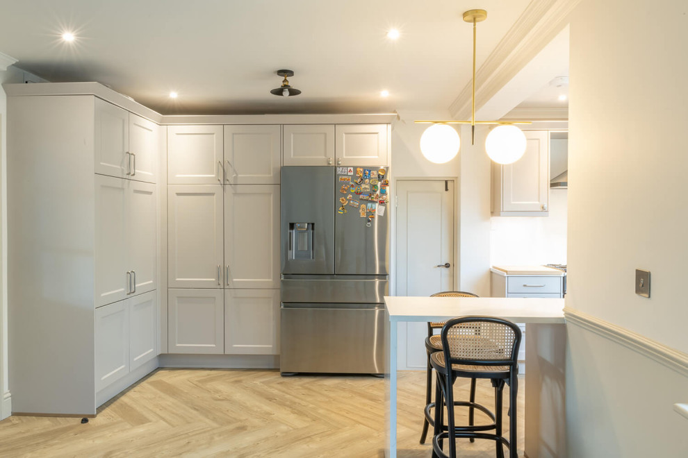 Photo of a medium sized grey and white u-shaped kitchen/diner in London with an integrated sink, recessed-panel cabinets, white cabinets, coloured appliances, no island, white worktops, exposed beams and a chimney breast.