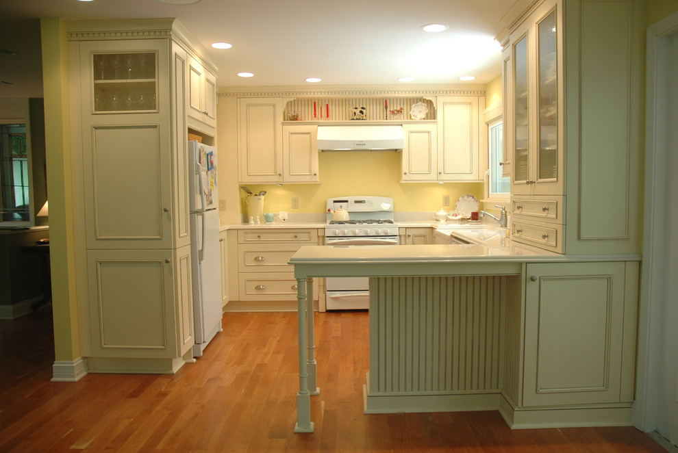 Photo of a traditional u-shaped separate kitchen in Indianapolis with an integrated sink, recessed-panel cabinets, yellow cabinets, white appliances, light hardwood floors, quartzite benchtops and yellow splashback.