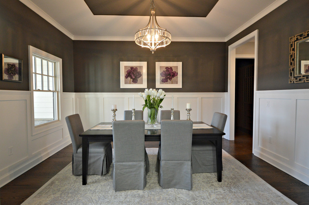 This is an example of a large traditional separate dining room in New York with grey walls, dark hardwood floors and a wood stove.