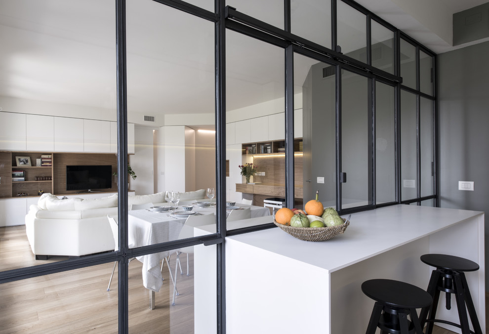 Inspiration for a mid-sized modern galley separate kitchen in Milan with an undermount sink, flat-panel cabinets, white cabinets, solid surface benchtops, grey splashback, glass sheet splashback, stainless steel appliances, light hardwood floors, with island and beige floor.
