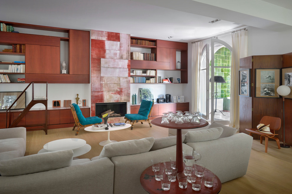 This is an example of a large mediterranean open concept living room in Paris with white walls, light hardwood floors, a standard fireplace, a library and no tv.