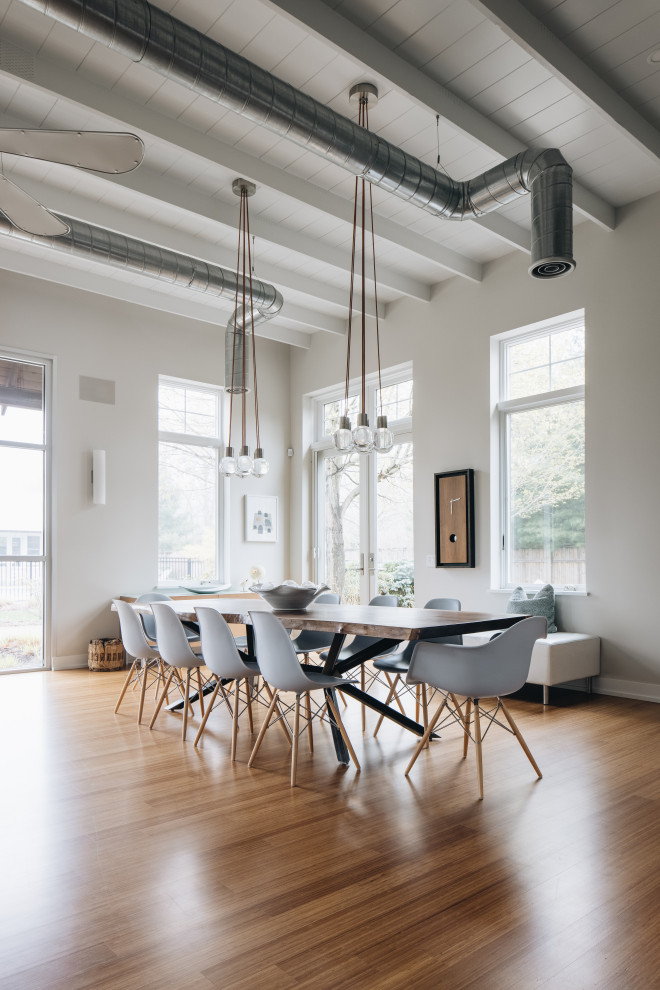 Immagine di una grande sala da pranzo aperta verso il soggiorno design con pareti grigie, parquet chiaro e soffitto in legno