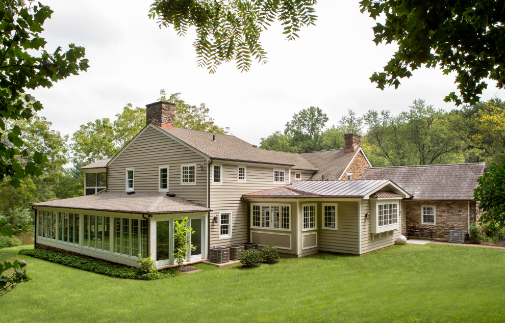 Cette photo montre une façade de maison beige nature en bois et bardeaux de taille moyenne et à un étage avec un toit en shingle et un toit marron.