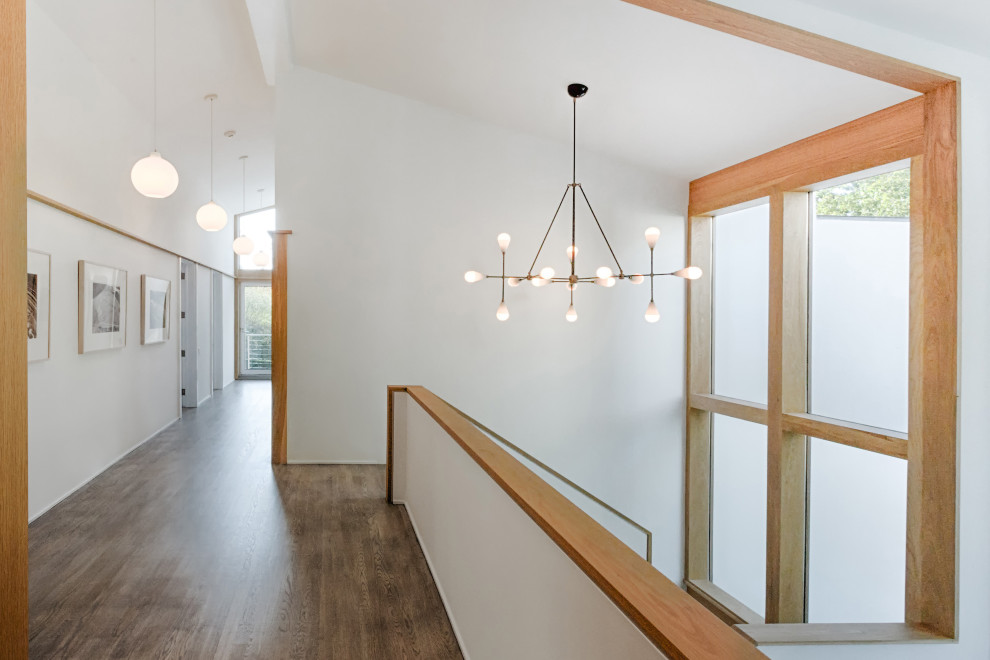 Photo of a large contemporary hallway in New York with white walls, light hardwood floors and beige floor.