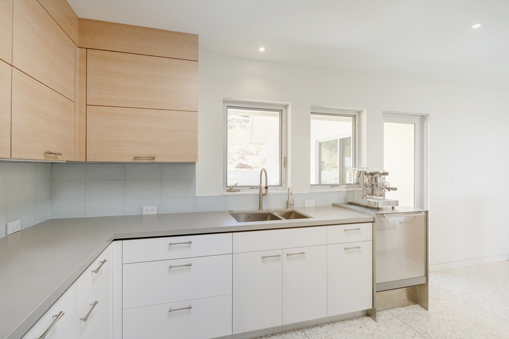 Inspiration for a small midcentury l-shaped open plan kitchen in Phoenix with an undermount sink, flat-panel cabinets, light wood cabinets, quartz benchtops, grey splashback, glass tile splashback, stainless steel appliances and with island.