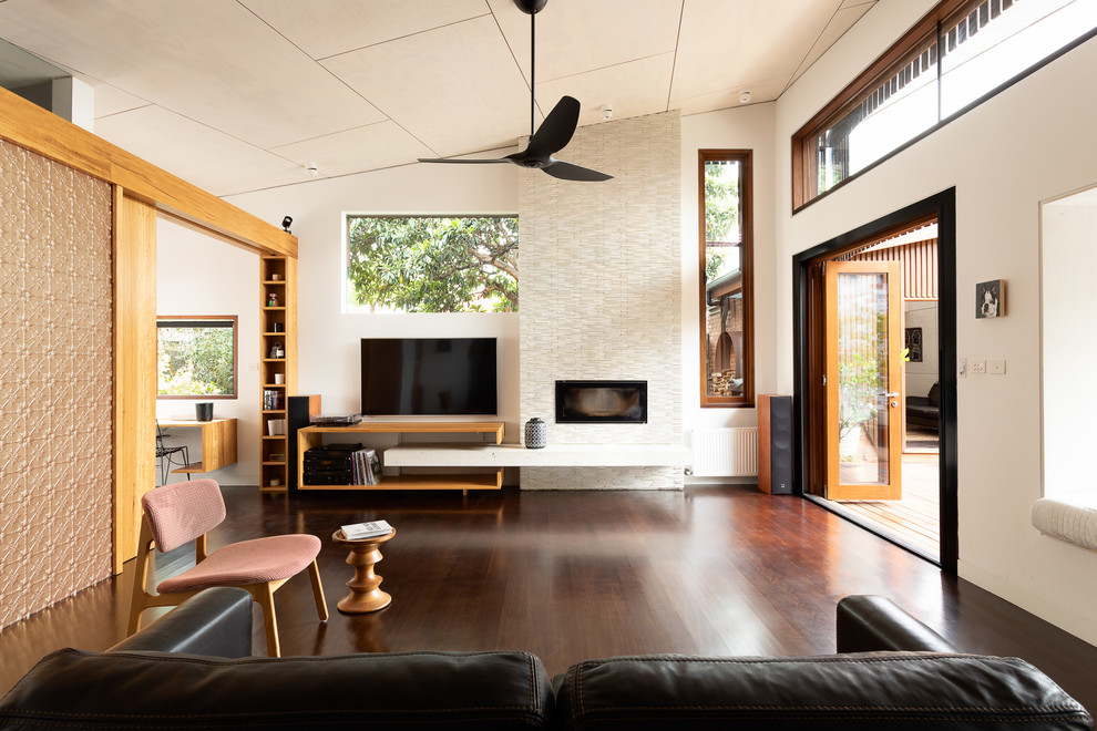 Inspiration for a contemporary open concept living room in Melbourne with white walls, dark hardwood floors, a standard fireplace, a tile fireplace surround, a wall-mounted tv and brown floor.