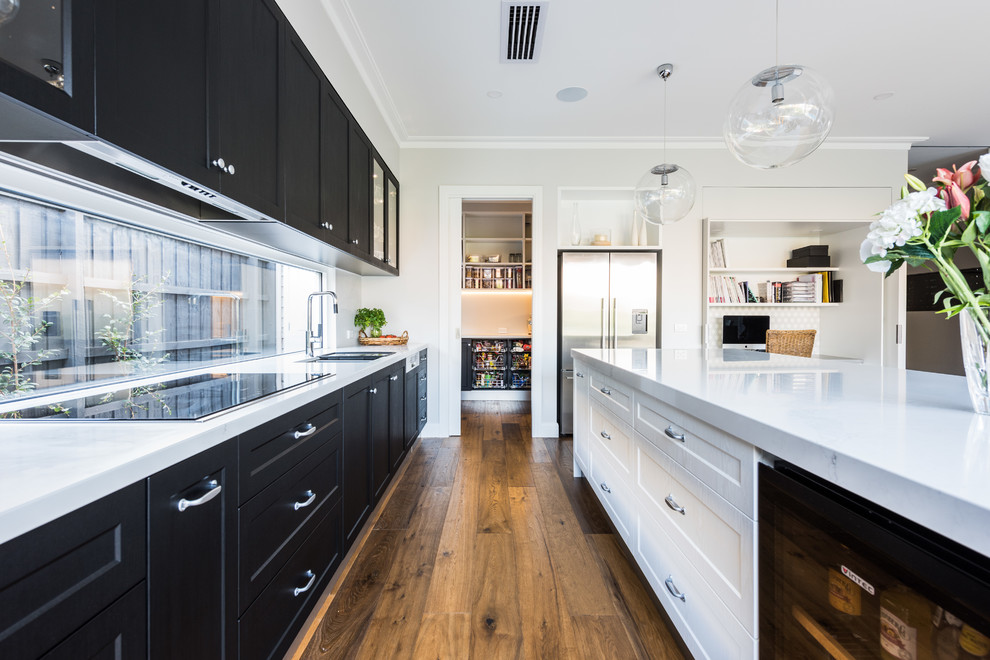 Mid-sized transitional u-shaped eat-in kitchen in Melbourne with a double-bowl sink, shaker cabinets, black cabinets, quartz benchtops, medium hardwood floors, no island and white benchtop.