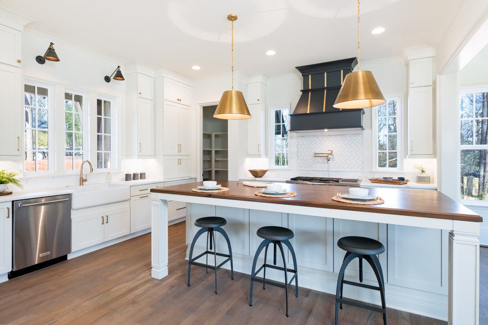 This is an example of a country l-shaped separate kitchen in Charlotte with a farmhouse sink, shaker cabinets, white cabinets, wood benchtops, white splashback, medium hardwood floors, with island, brown floor and brown benchtop.