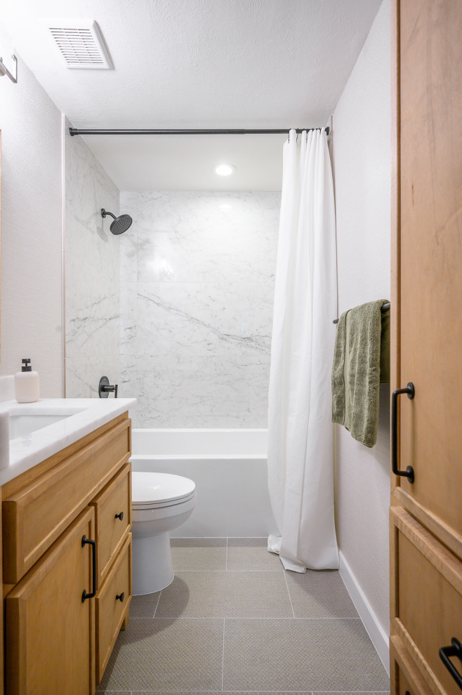 Идея дизайна: маленькая главная ванная комната в стиле модернизм с фасадами в стиле шейкер, светлыми деревянными фасадами, ванной в нише, душем над ванной, раздельным унитазом, белой плиткой, керамогранитной плиткой, бежевыми стенами, полом из керамогранита, врезной раковиной, мраморной столешницей, серым полом, шторкой для ванной, белой столешницей, нишей, тумбой под одну раковину, встроенной тумбой и обоями на стенах для на участке и в саду