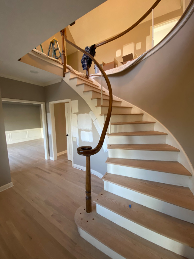 Modelo de escalera curva minimalista grande con escalones de madera, contrahuellas de madera pintada, barandilla de madera y madera