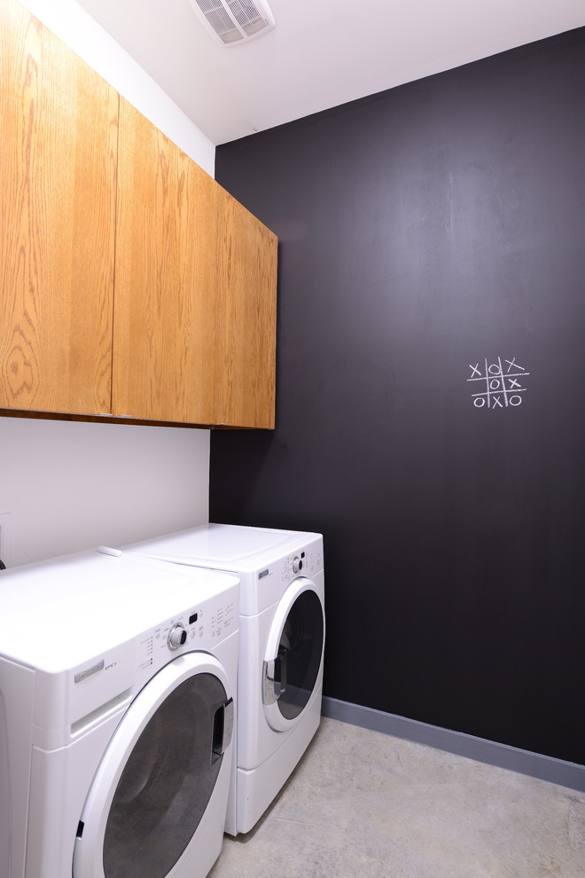 This is an example of a small contemporary single-wall dedicated laundry room in Dallas with a side-by-side washer and dryer, an undermount sink, flat-panel cabinets, quartz benchtops, white walls, concrete floors and medium wood cabinets.