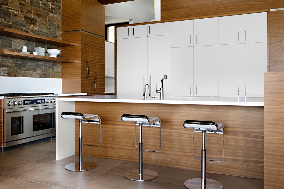 This is an example of a large modern u-shaped eat-in kitchen in Phoenix with a drop-in sink, recessed-panel cabinets, medium wood cabinets, marble benchtops, white splashback, stone slab splashback, stainless steel appliances, limestone floors, with island and beige floor.