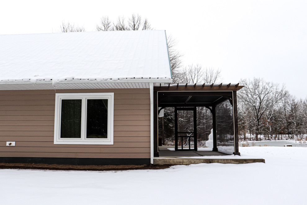 Cette image montre une façade de maison marron traditionnelle en bois et bardage à clin de taille moyenne et de plain-pied avec un toit à deux pans et un toit en métal.
