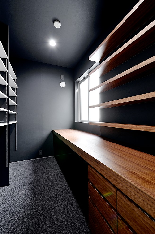 This is an example of a modern study room in Tokyo Suburbs with black walls, a built-in desk, carpet, no fireplace and grey floor.