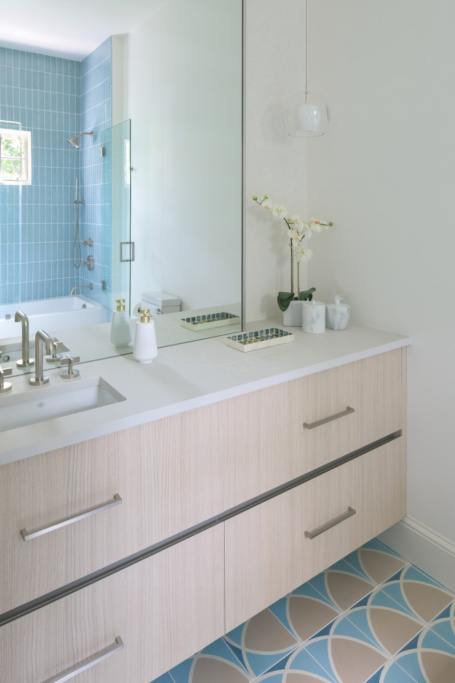 This is an example of a mid-sized modern kids bathroom in DC Metro with flat-panel cabinets, beige cabinets, an alcove tub, a shower/bathtub combo, a one-piece toilet, blue tile, porcelain tile, white walls, cement tiles, an undermount sink, engineered quartz benchtops, blue floor, a hinged shower door, white benchtops, a shower seat, a single vanity and a floating vanity.