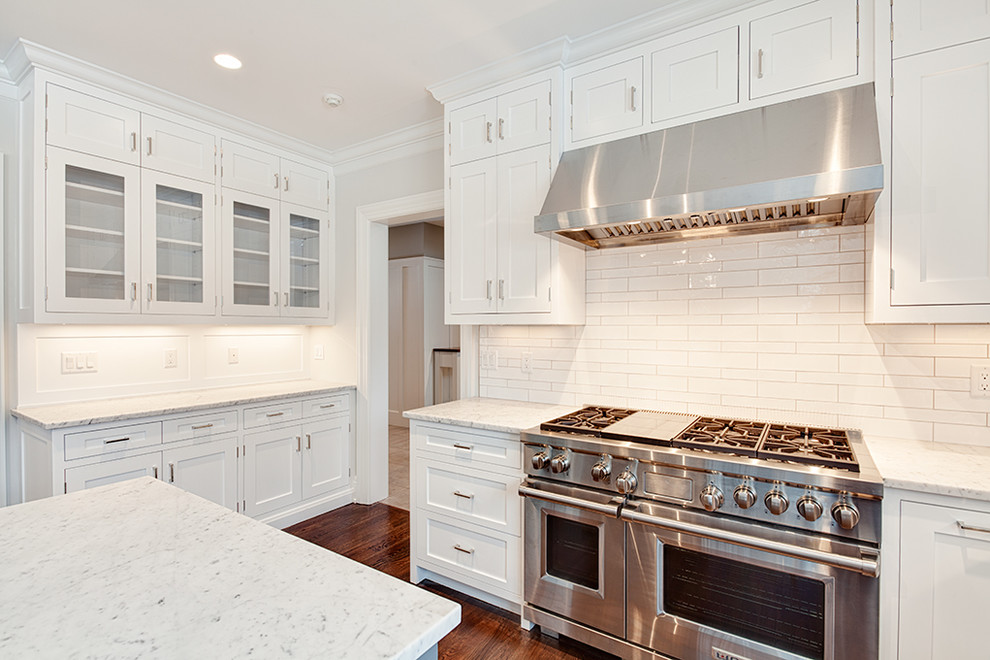 Eat-in kitchen - large transitional u-shaped dark wood floor and brown floor eat-in kitchen idea with an undermount sink, shaker cabinets, white cabinets, white backsplash, stainless steel appliances and an island