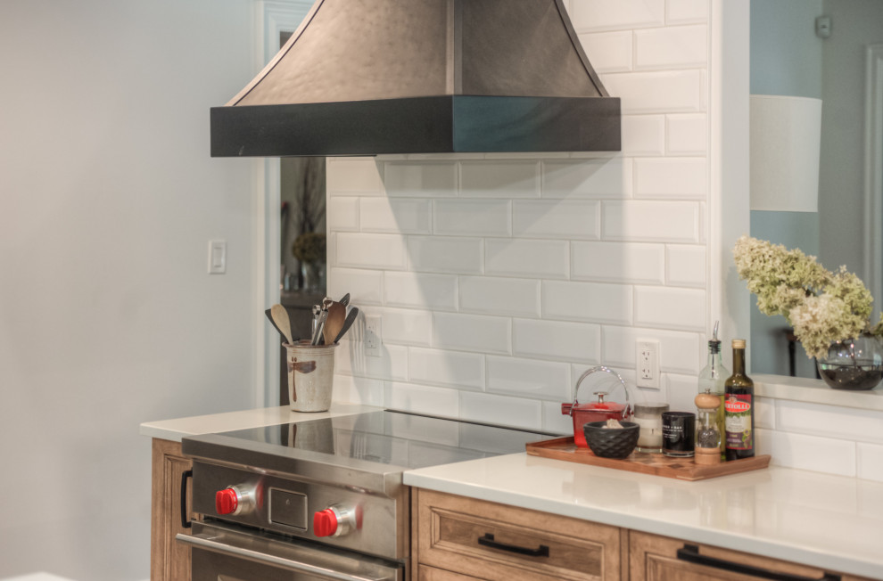 Transitional l-shaped kitchen photo in Toronto with an undermount sink, shaker cabinets, light wood cabinets, white backsplash, stainless steel appliances, an island and white countertops