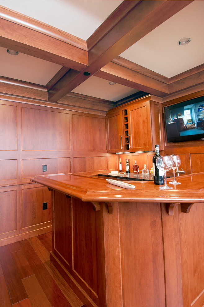 This is an example of a small traditional u-shaped seated home bar in Other with an undermount sink, shaker cabinets, medium wood cabinets, granite benchtops and medium hardwood floors.