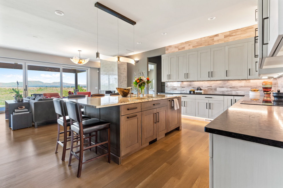 Eat-in kitchen - mid-sized transitional galley medium tone wood floor and brown floor eat-in kitchen idea in Denver with an undermount sink, flat-panel cabinets, beige backsplash and an island