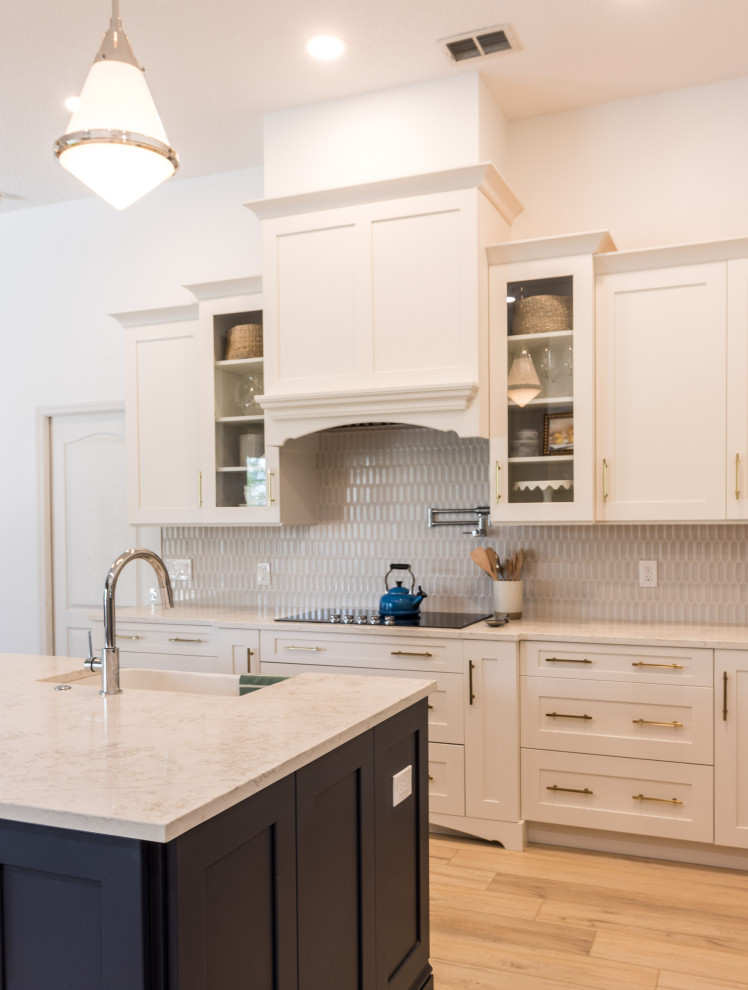 Inspiration for a transitional vinyl floor and gray floor kitchen remodel in Orlando with an undermount sink, recessed-panel cabinets, blue cabinets, quartzite countertops, gray backsplash, porcelain backsplash, stainless steel appliances, an island and white countertops