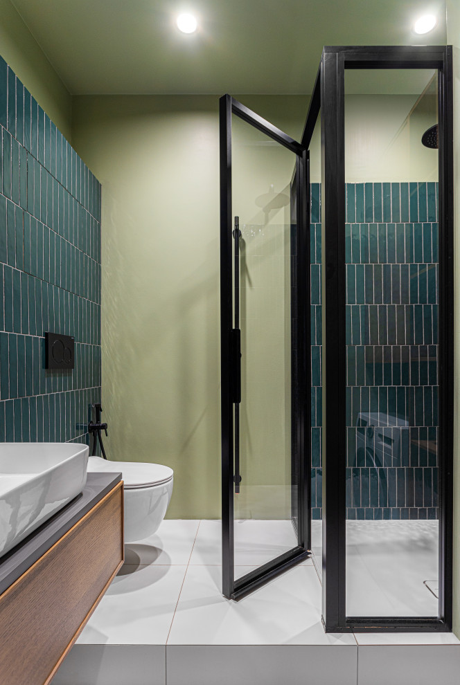 Photo of a small shower room bathroom in Moscow with raised-panel cabinets, brown cabinets, an alcove shower, a wall mounted toilet, green tiles, ceramic tiles, green walls, a built-in sink, solid surface worktops, white floors, a hinged door, grey worktops, feature lighting, a single sink and a floating vanity unit.