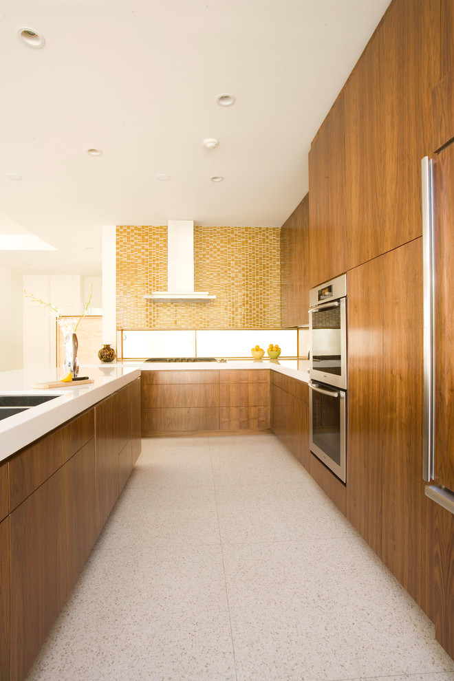 Photo of a mid-sized midcentury l-shaped eat-in kitchen in Los Angeles with an undermount sink, flat-panel cabinets, medium wood cabinets, quartz benchtops, beige splashback, mosaic tile splashback, panelled appliances and with island.