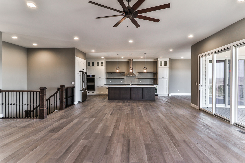 Inspiration for a large transitional single-wall open plan kitchen in St Louis with a farmhouse sink, shaker cabinets, white cabinets, quartzite benchtops, stainless steel appliances, dark hardwood floors, with island and brown floor.