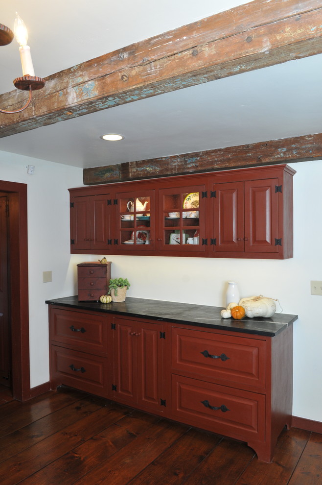 Inspiration for a mid-sized country l-shaped kitchen in Orange County with a farmhouse sink, raised-panel cabinets, red cabinets, soapstone benchtops, beige splashback, subway tile splashback, stainless steel appliances, medium hardwood floors, with island and beige floor.