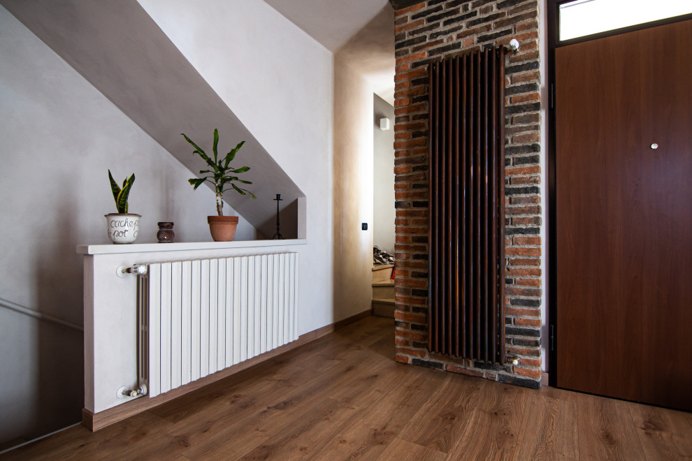 Foto di un piccolo soggiorno industriale aperto con pavimento in laminato e pareti in mattoni