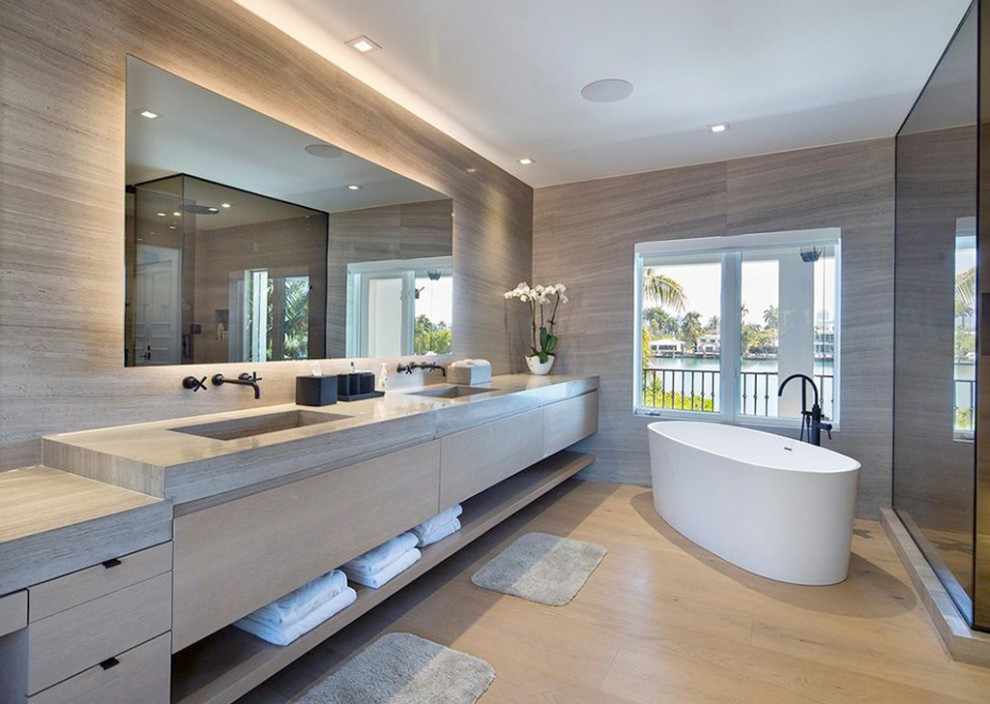Photo of an expansive modern master wet room bathroom in Miami with flat-panel cabinets, medium wood cabinets, a freestanding tub, a wall-mount toilet, brown tile, marble, brown walls, medium hardwood floors, an integrated sink, marble benchtops, brown floor, a hinged shower door, brown benchtops, a shower seat, a double vanity and a floating vanity.