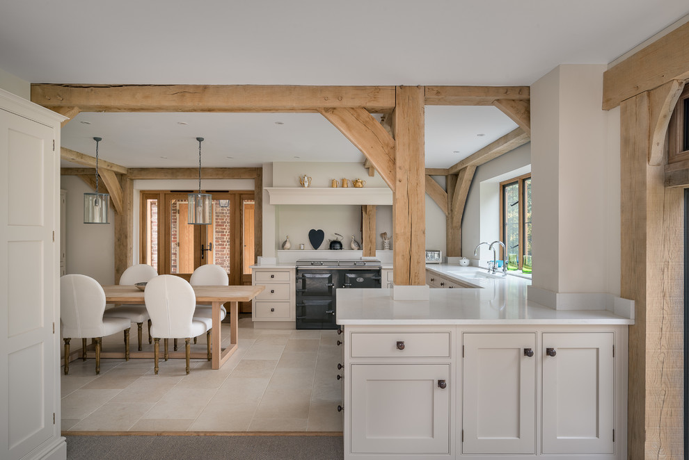 This is an example of a large country u-shaped open plan kitchen in Surrey with an undermount sink, recessed-panel cabinets, beige cabinets, granite benchtops, beige splashback, panelled appliances, limestone floors and no island.