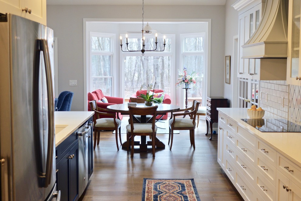 Eat-in kitchen - large transitional galley medium tone wood floor and brown floor eat-in kitchen idea in Cleveland with an undermount sink, shaker cabinets, white cabinets, quartzite countertops, white backsplash, subway tile backsplash, stainless steel appliances and a peninsula