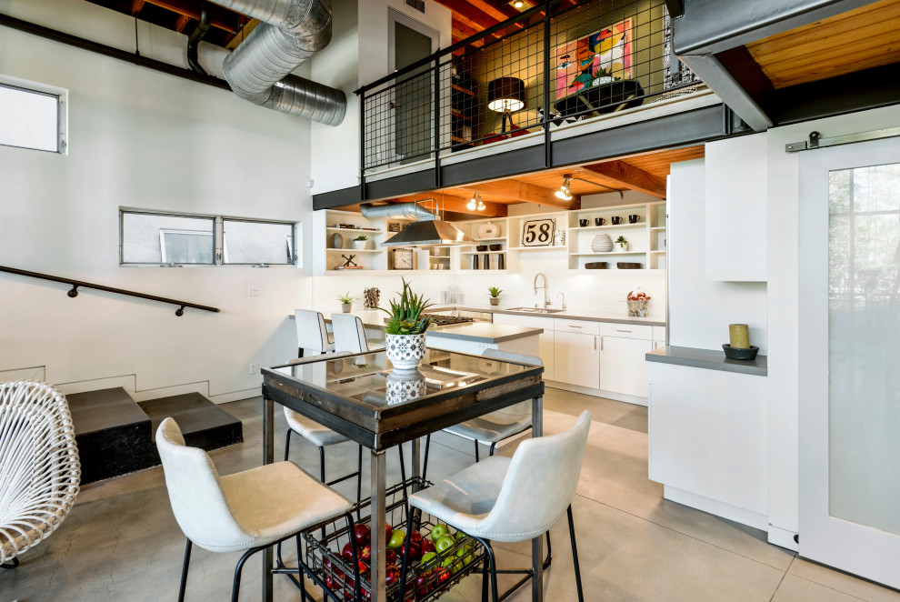 This is an example of an industrial open plan dining in Los Angeles with white walls, concrete floors and grey floor.