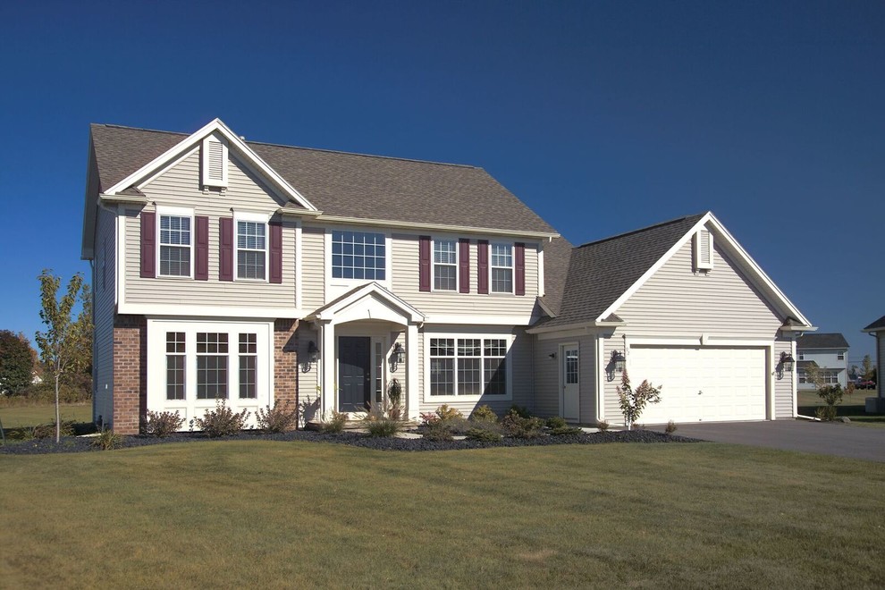 Photo of a large traditional two-storey grey house exterior in Other with a hip roof, a shingle roof and vinyl siding.