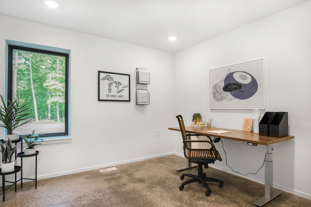 Mid-sized modern study room in Grand Rapids with white walls, carpet, no fireplace, a freestanding desk and brown floor.