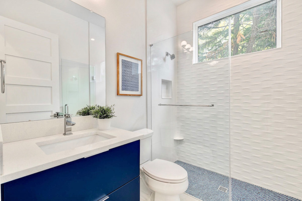 Photo of a mid-sized modern 3/4 bathroom in Tampa with flat-panel cabinets, blue cabinets, an alcove shower, white tile, ceramic tile, white walls, ceramic floors, an undermount sink, engineered quartz benchtops, brown floor, a hinged shower door, white benchtops, a single vanity and a floating vanity.