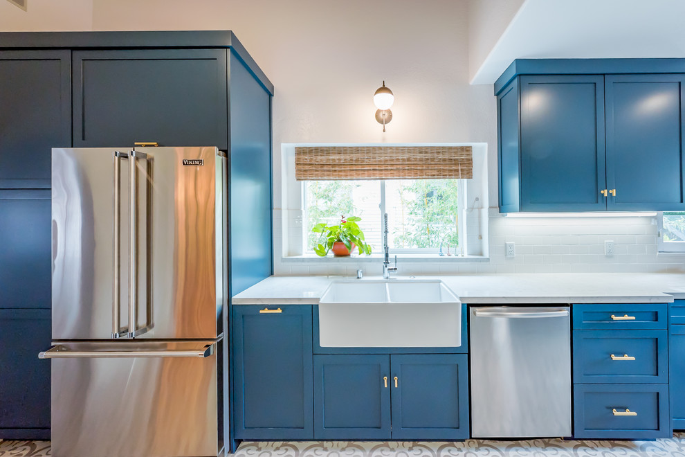 Mid-sized contemporary galley separate kitchen in Los Angeles with a farmhouse sink, shaker cabinets, blue cabinets, quartzite benchtops, white splashback, subway tile splashback, stainless steel appliances, cement tiles, no island and white floor.