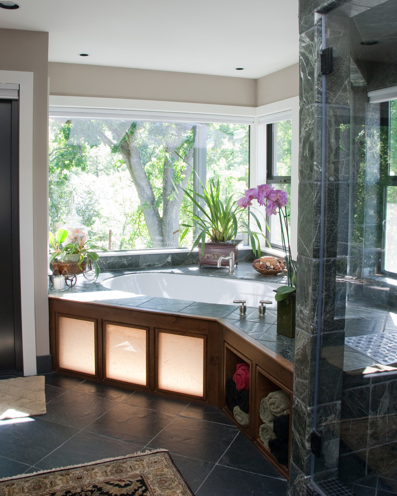 Inspiration for a mid-sized transitional master bathroom in San Francisco with flat-panel cabinets, medium wood cabinets, marble benchtops, a corner tub, an alcove shower, green tile, stone tile, grey walls, slate floors, black floor and a sliding shower screen.