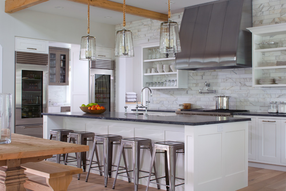 Inspiration for a transitional single-wall kitchen in Grand Rapids with a farmhouse sink, white cabinets, soapstone benchtops, white splashback, porcelain splashback, stainless steel appliances, light hardwood floors and with island.