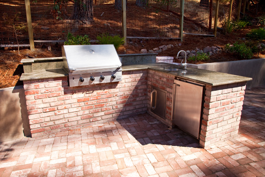 This is an example of a mediterranean backyard patio in San Francisco with an outdoor kitchen, brick pavers and no cover.