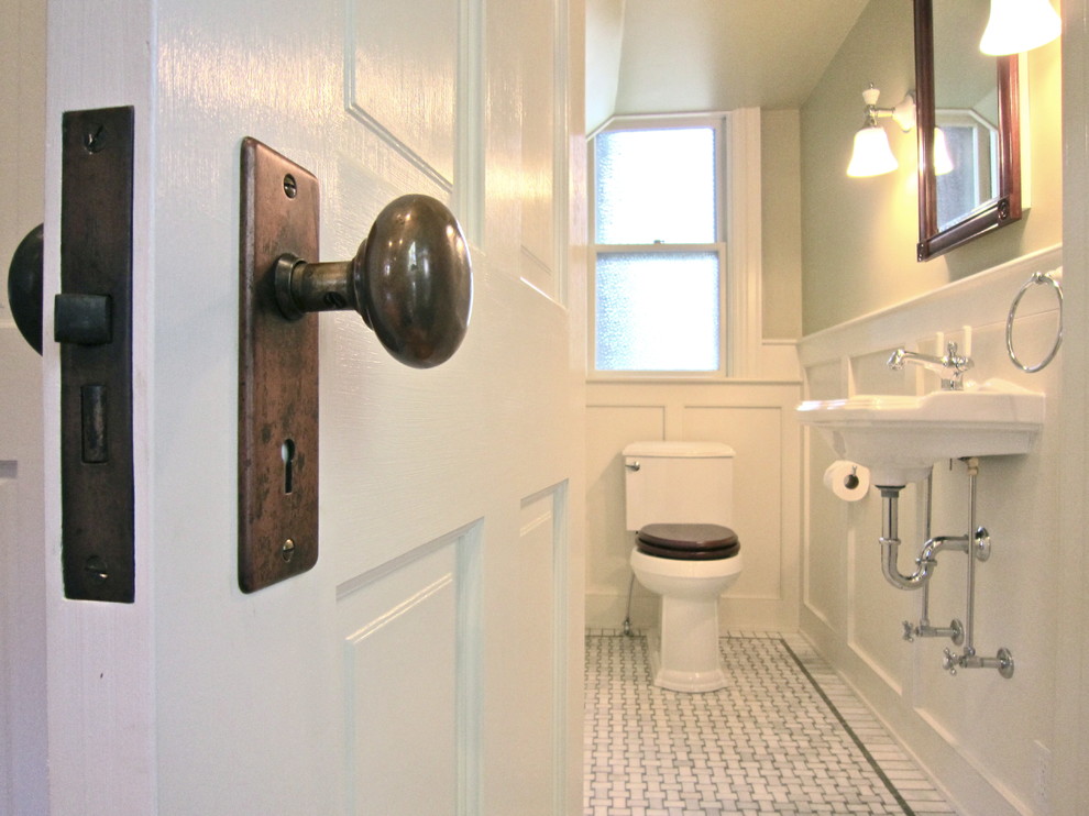 This is an example of a small traditional powder room in Boston with a wall-mount sink, a two-piece toilet, multi-coloured tile, beige tile and gray tile.