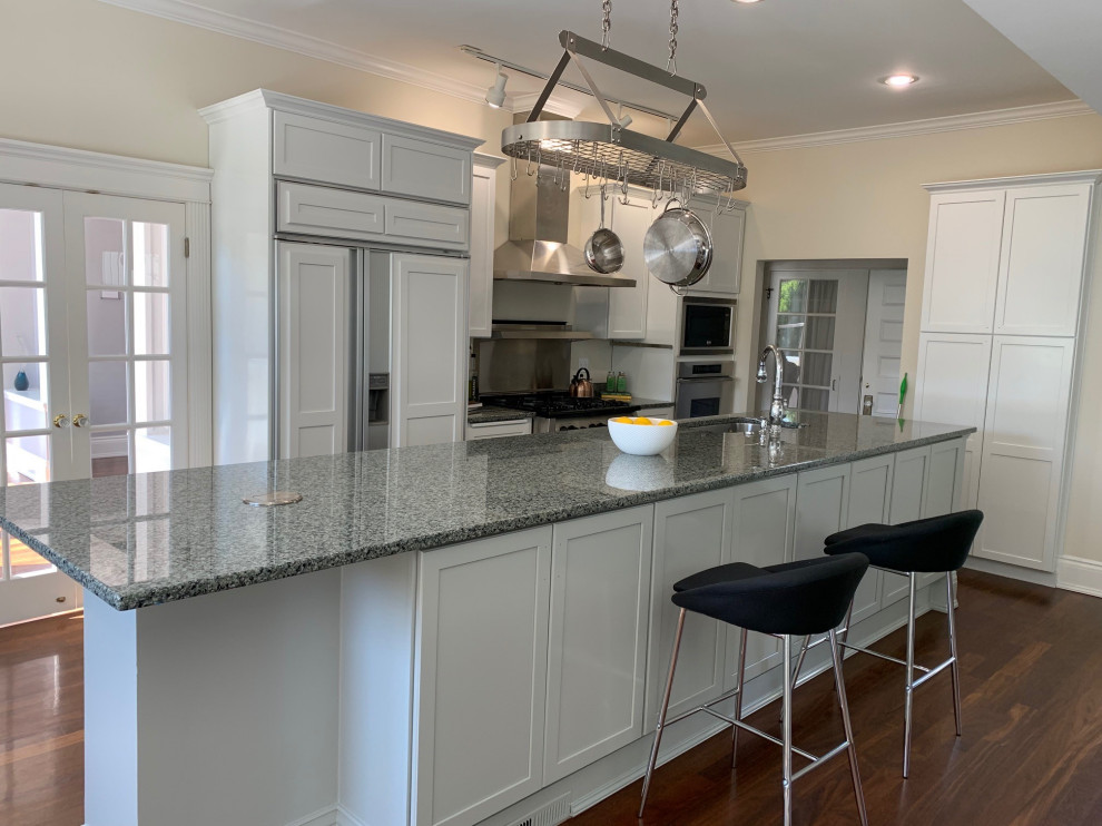 Large transitional single-wall dark wood floor and brown floor enclosed kitchen photo in Seattle with an undermount sink, shaker cabinets, white cabinets, granite countertops, gray backsplash, metal backsplash, stainless steel appliances, an island and gray countertops