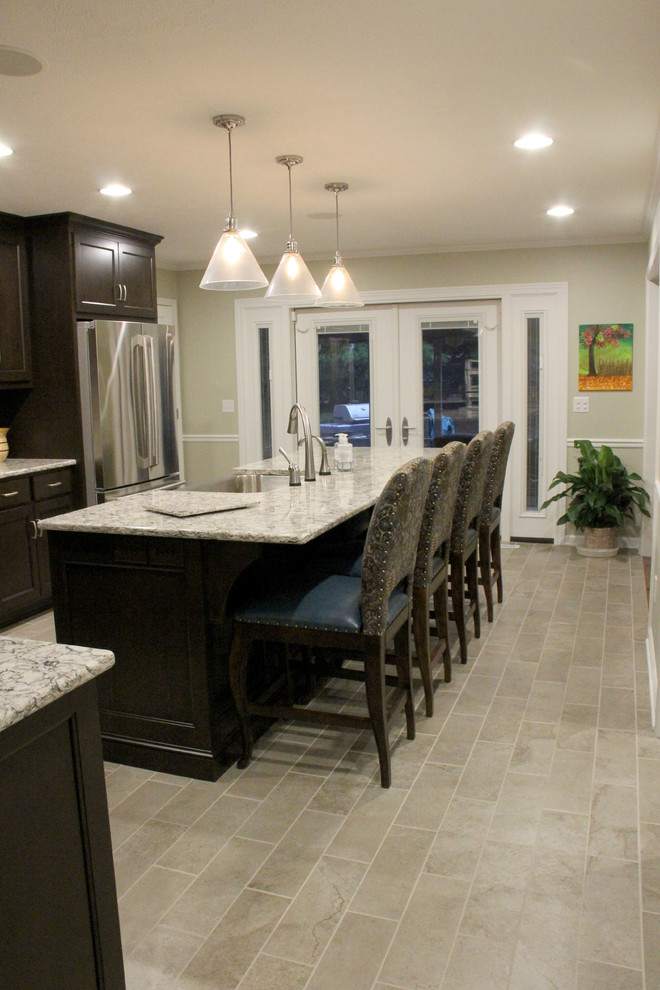 Mid-sized transitional l-shaped porcelain tile enclosed kitchen photo with a farmhouse sink, recessed-panel cabinets, dark wood cabinets, quartz countertops, glass tile backsplash, stainless steel appliances and an island