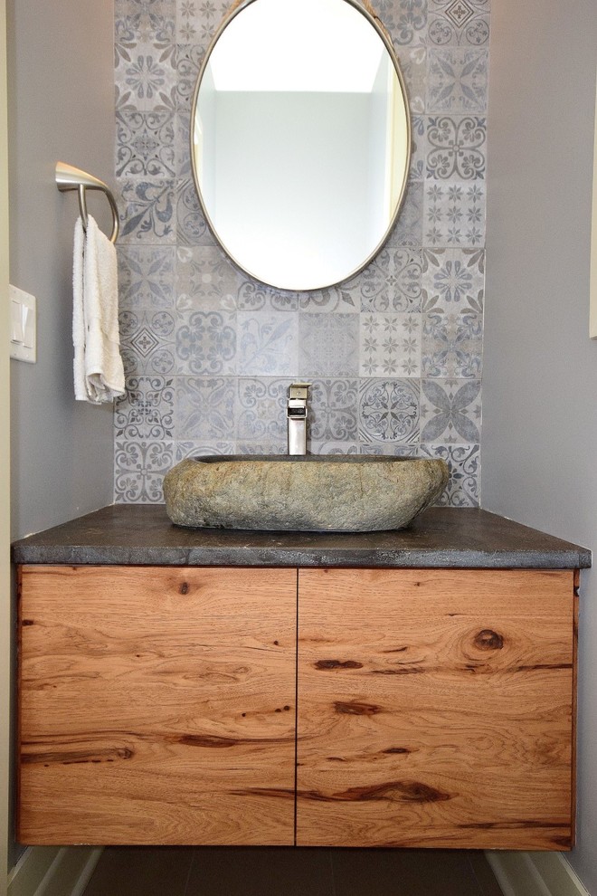 Design ideas for a scandinavian powder room in Chicago with flat-panel cabinets, medium wood cabinets, gray tile, ceramic tile, grey walls, porcelain floors, a vessel sink, soapstone benchtops, grey floor and grey benchtops.