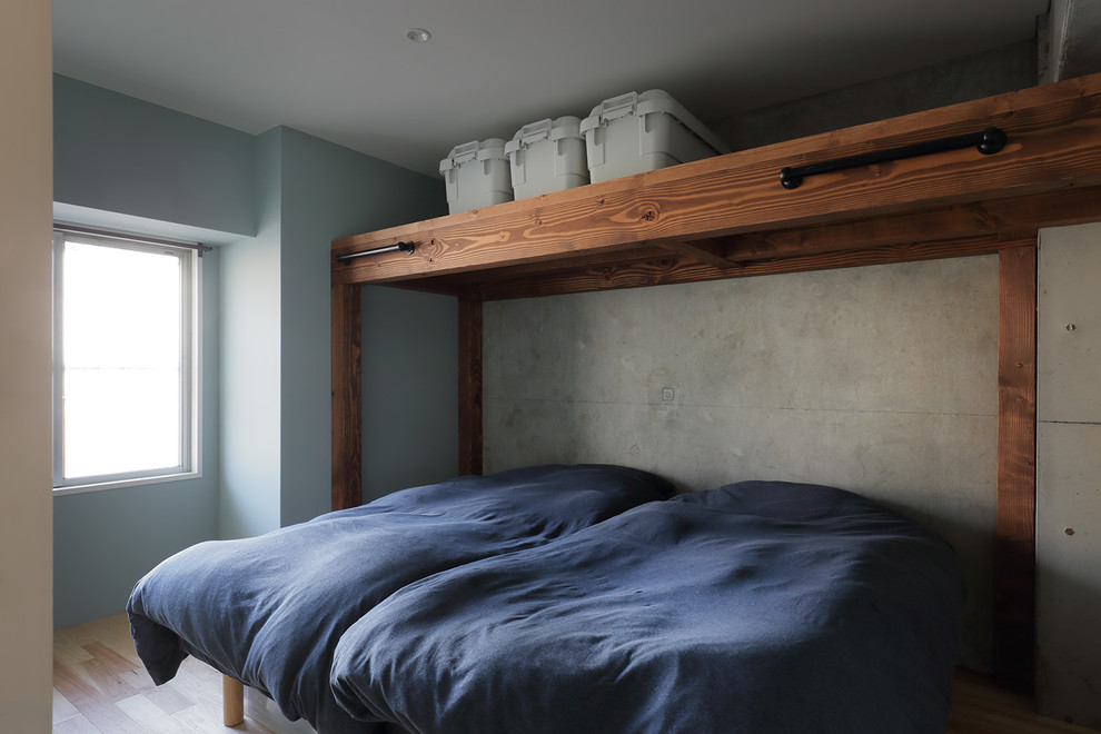 Inspiration for a small industrial master bedroom in Other with blue walls, medium hardwood floors, no fireplace and brown floor.