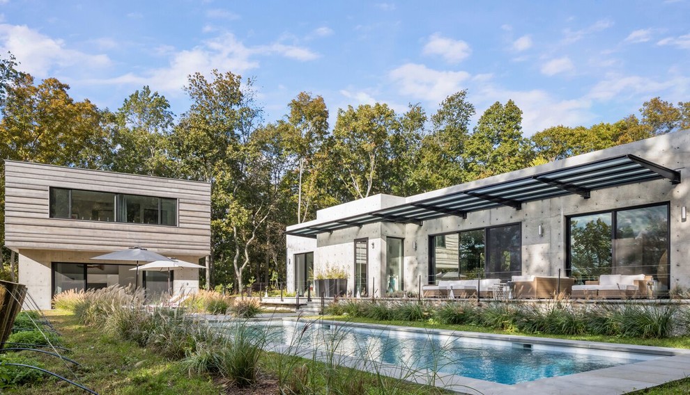 This is an example of a large contemporary grey house exterior in New York with a flat roof.